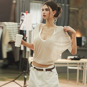 Detail shot of a beige V-neck knitted top with short sleeves in a soft lifestyle setting