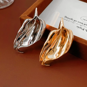 Detailed view of abstract gold and silver leaf brooches with irregular wave textures