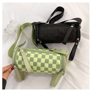 Detail of cylinder crossbody bags showing green checkerboard and black seersucker textures