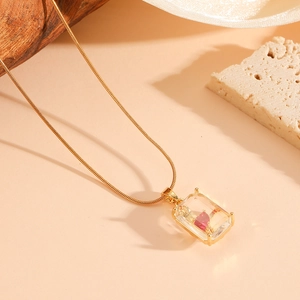 Détail d'un pendentif coeur rouge en cristal doré sur une fine chaîne serpent