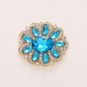 Macro detail of luxury flower brooch with blue crystal gemstone and sparkling rhinestones