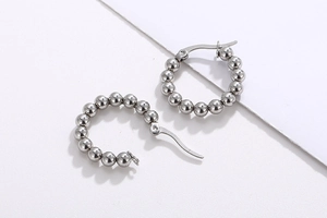 Detailed close-up of French minimalist silver steel bead hoop earrings on white background