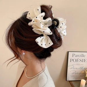 Detailed back view of a large cream silk bow hair claw with elegant black polka dots