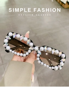 Close-up of square sunglasses with embedded pearls and rainbow crystals on black frame