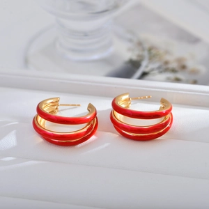 Macro view of triple-layered red and gold hoop earrings with polished enamel finish