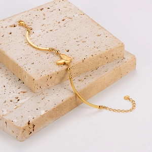 Elegant gold butterfly bracelet displayed on textured beige stones in light luxury style