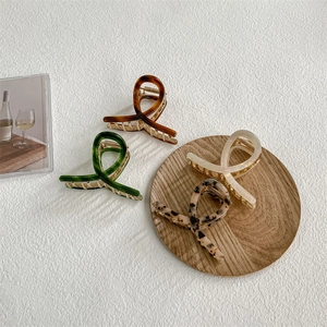 Chic acetate hair claws in tortoise shell and cream colors on a white textured background