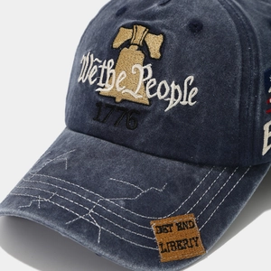 Macro shot of 1776 embroidery and We the People text on washed blue canvas baseball cap