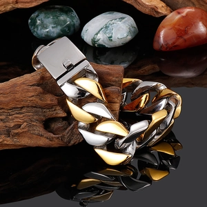 Macro view of two-tone gold and silver 20mm Cuban chain bracelet on dark stone base