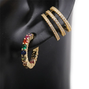 Detail of colorful gemstone earrings and gold three-row diamond ear cuffs on ear model