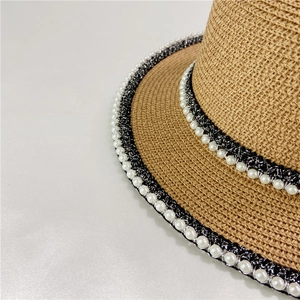 Detail of vintage straw hat featuring pearl trim and shimmering black ribbon accents