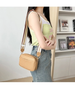 Side view of light brown textured crossbody bag with striped wide shoulder strap
