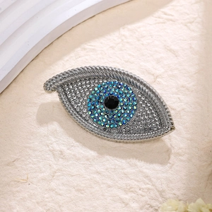 Macro shot of silver Evil Eye brooch with blue crystals and woven metal texture