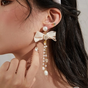 Asymmetric beige bow earrings with imitation pearls and long elegant tassel design
