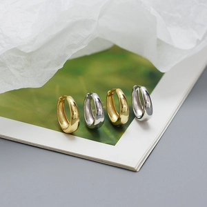 Detailed macro shot of minimalist S925 sterling silver hoop earrings in gold and silver