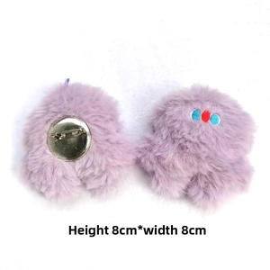 Detail of plush purple monster brooch showing soft texture and metal safety pin back