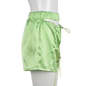 Detail of neon green satin shorts featuring side cut-outs and adjustable drawstrings