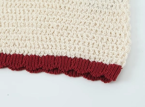 Macro view of knit polo set featuring cream hollow stitch and red ribbed hem detail