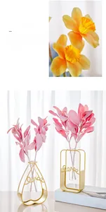 Detail of silk narcissus bouquet in gold geometric metal frame glass vase decoration