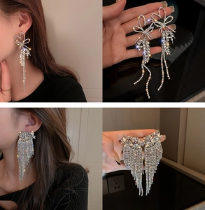 Detail of silver bow and fan-shaped earrings with long sparkling rhinestone tassels