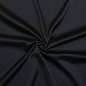 Macro view of silky black satin fabric with elegant light-reflective draped folds