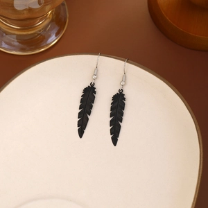 Detailed macro view showing the texture of black feather drop earrings on a ceramic dish