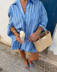 Close-up of blue striped cotton shirt paired with a woven straw tote bag for summer