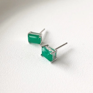 Macro shot of rectangular emerald green zircon stud earrings with silver 4-claw setting