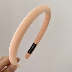 Close-up of a pink macaron sponge headband featuring a black 'Hand Made' woven label