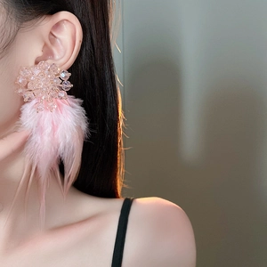 Close-up of elegant pink crystal cluster earrings with soft feather tassels on a model