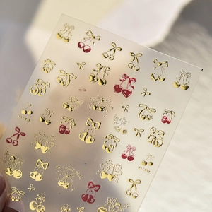 Gold cherry and bow nail art stickers featuring metal finish patterns on clear backing