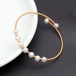 Detail of gold spiral bracelet featuring white freshwater pearls and golden spacer beads