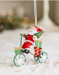 Close-up of Santa Claus on a tricycle with gifts and mini tree on snowy background