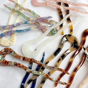 Minimalist U-shaped acetate hair pins in various marble colors on white fabric