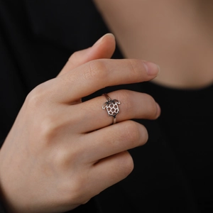 Macro shot of a silver turtle cutout ring in stainless steel worn on a model finger