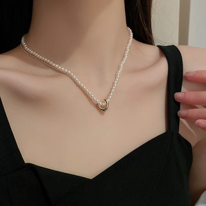 Close-up of double-layer pearl necklace with a gold heart pendant on model