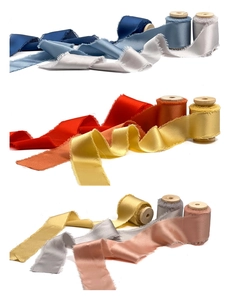 Frayed edge handmade ribbons on wooden spools showing soft silk texture and fringe details