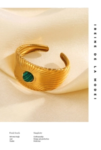 Detailed macro view of a gold-tone radial texture ring featuring a green round gemstone