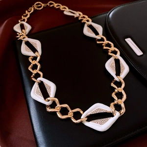 Close-up of golden chain necklace with white diamond-encrusted geometric rhombuses