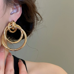 Gros plan de boucles d'oreilles créoles dorées avec anneaux métalliques entrelacés