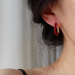Close-up of a U-shaped earring in polished 18k gold plating with a vibrant red enamel finish