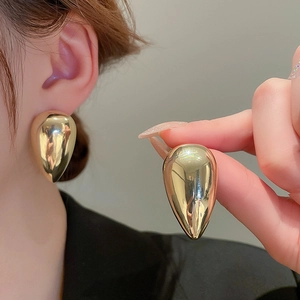 Macro view of gold teardrop earrings showing large size and polished metallic finish