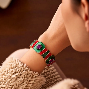 Detail of vintage enamel bracelet featuring green and red patterns with purple gemstones