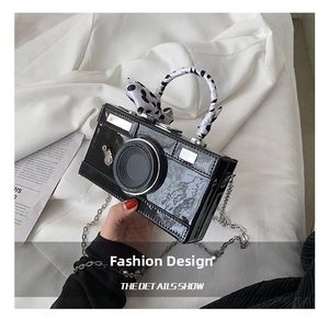 Detail of camera-shaped crossbody bag with polka dot ribbon and silver chain strap