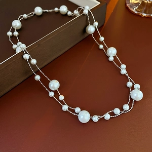 Macro detail of double-layer pearl necklace with silver chain in a wooden jewelry box