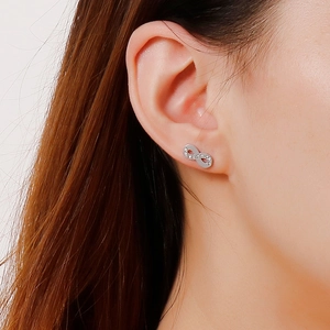 Close-up of infinity symbol stud earrings with white zircons on a model's ear
