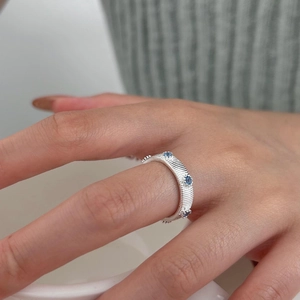 Detail of S925 silver ring with horizontal texture and three blue zircons on finger