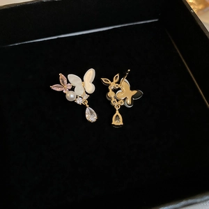 Detail of gold butterfly earrings with pearl and teardrop zircon on black velvet