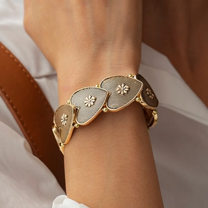 Detail of vintage gold heart-shaped bracelet with embossed floral patterns on links