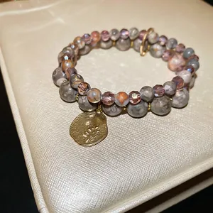 Double-layered beaded bracelet featuring stone beads, purple crystal and leaf pendant